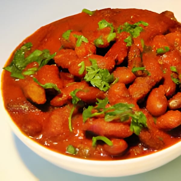 A close-up of Indian Rajma Chawal, red kidney beans in a rich, spicy tomato gravy, garnished with fresh cilantro.