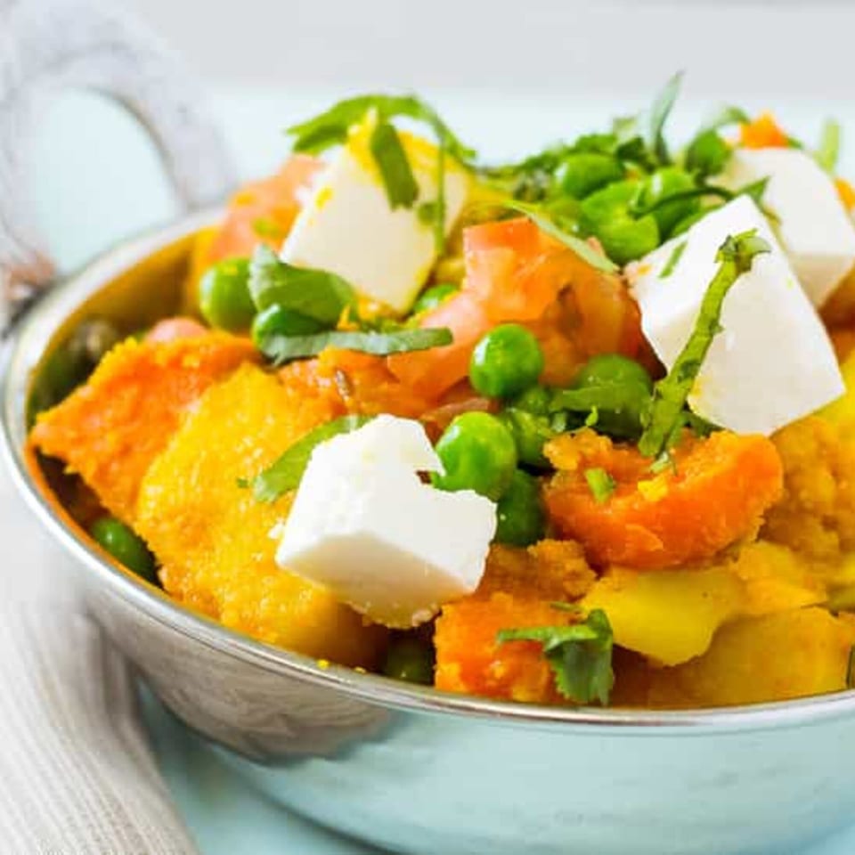 Close-up of Indian Chaat with paneer, peas, and vegetables in a silver bowl.