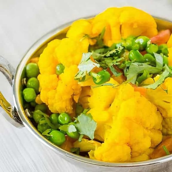 Chaat House's Aloo Gobi, a vibrant Indian dish with yellow cauliflower, green peas, and cilantro.